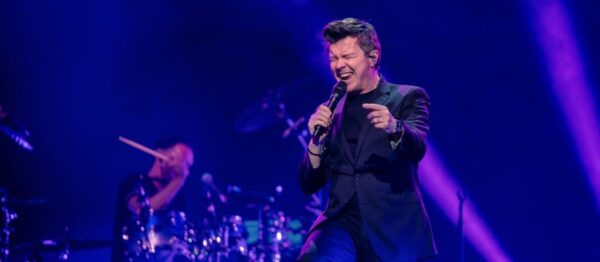 Rick Astley perfoming live on stage in front of his fans.