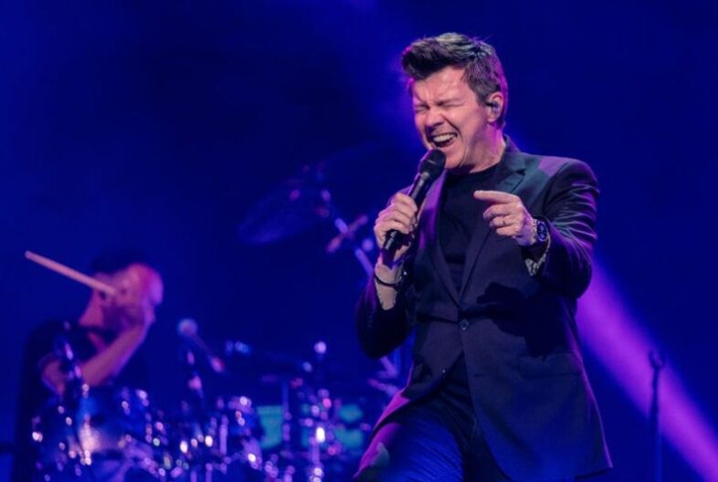 Rick Astley perfoming live on stage in front of his fans.