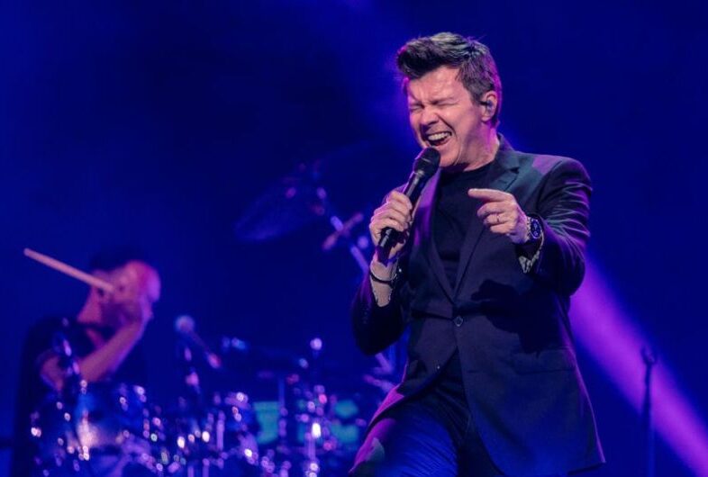 Rick Astley perfoming live on stage in front of his fans.